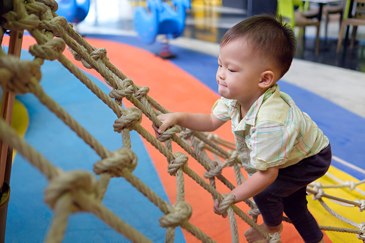 Young child climbing a rope ladder, demonstrating physical activity that supports baby brain development and motor skill growth.