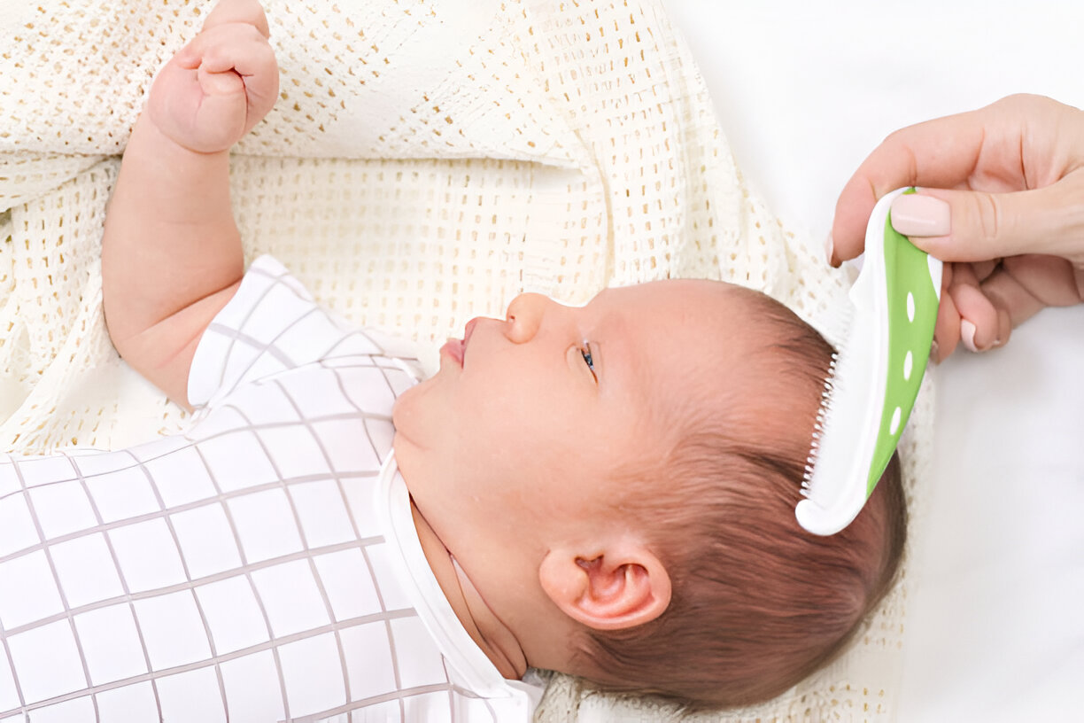 A serene newborn baby lying on a soft blanket while an adult gently combs the baby’s hair. The image captures a calming moment, reflecting nurturing care, perfect for discussions about white noise machines and infant sleep solutions.