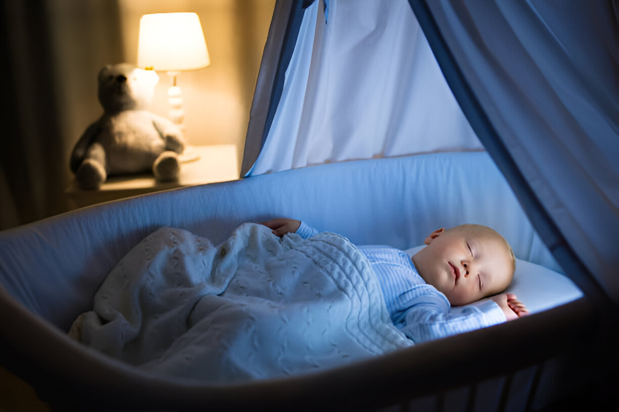 A peacefully sleeping newborn in a softly lit crib, wrapped in a cozy blanket during overnight newborn care, with a warm bedside lamp and a teddy bear adding a comforting ambiance in the background.